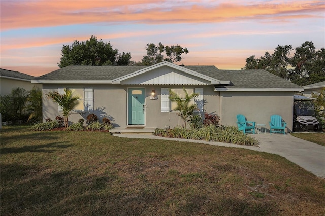 single story home with driveway, stucco siding, a shingled roof, and a front yard