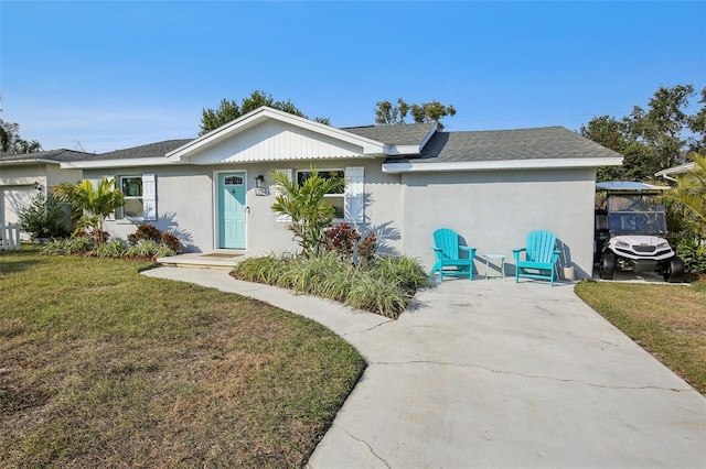 ranch-style house featuring stucco siding, a front yard, and roof with shingles