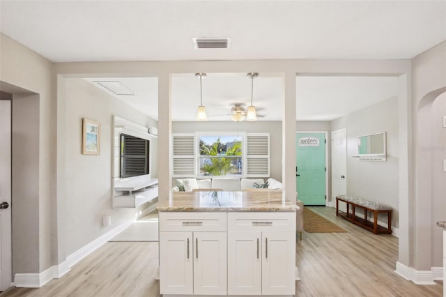 kitchen with visible vents, hanging light fixtures, white cabinetry, light stone countertops, and light wood-type flooring