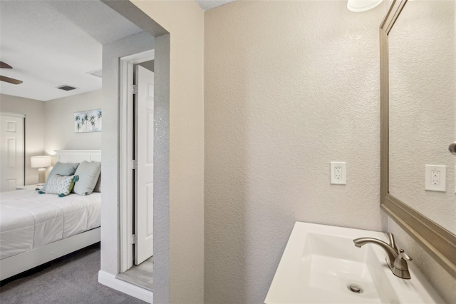 bathroom featuring a textured wall, visible vents, vanity, a ceiling fan, and ensuite bath