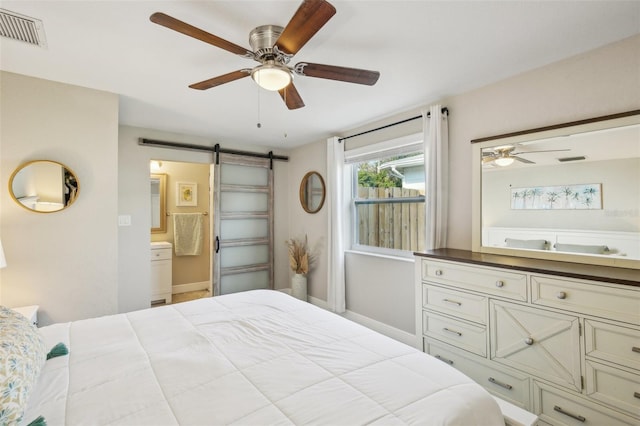 bedroom featuring ensuite bathroom, a barn door, visible vents, and a ceiling fan