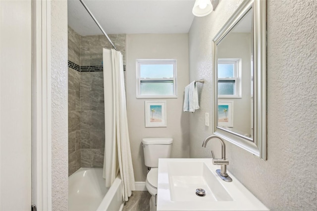 bathroom featuring a textured wall, shower / tub combo with curtain, a sink, and toilet