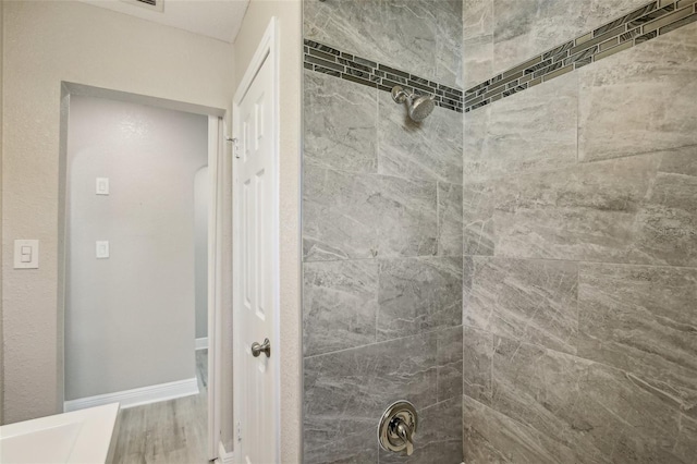 bathroom with baseboards and a tile shower