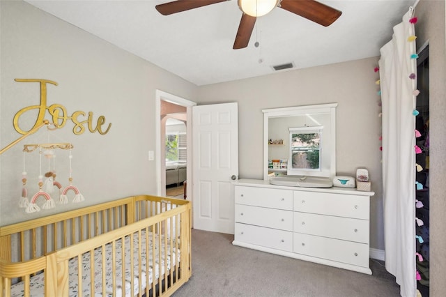 bedroom with a nursery area, ceiling fan, visible vents, and light colored carpet