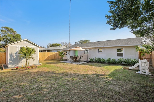 back of property with a lawn, a patio, a fenced backyard, a storage unit, and an outdoor structure