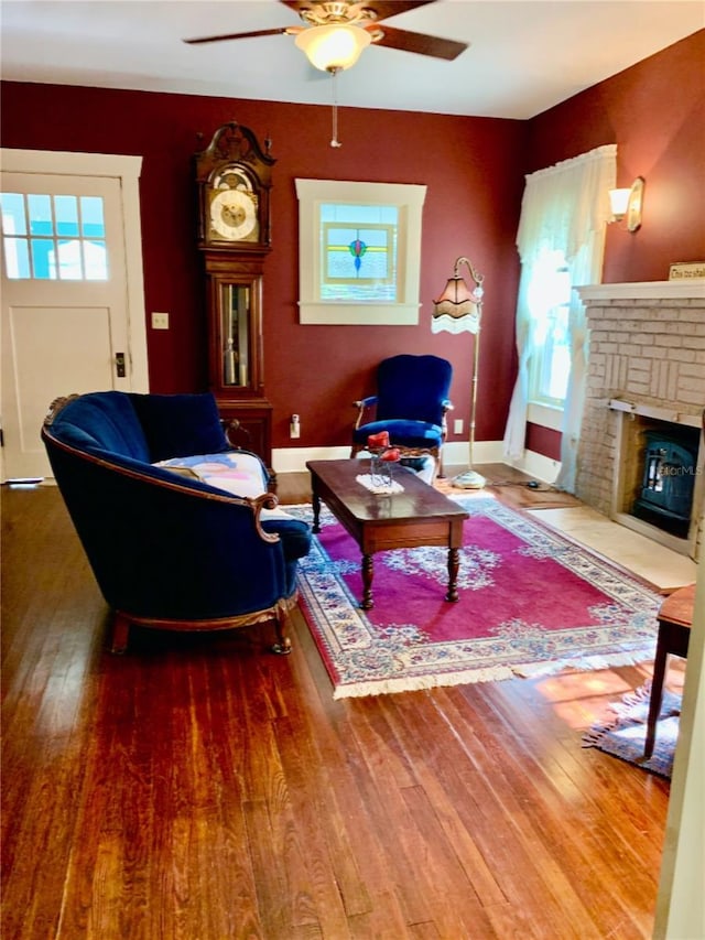 living room with hardwood / wood-style flooring, ceiling fan, and a brick fireplace