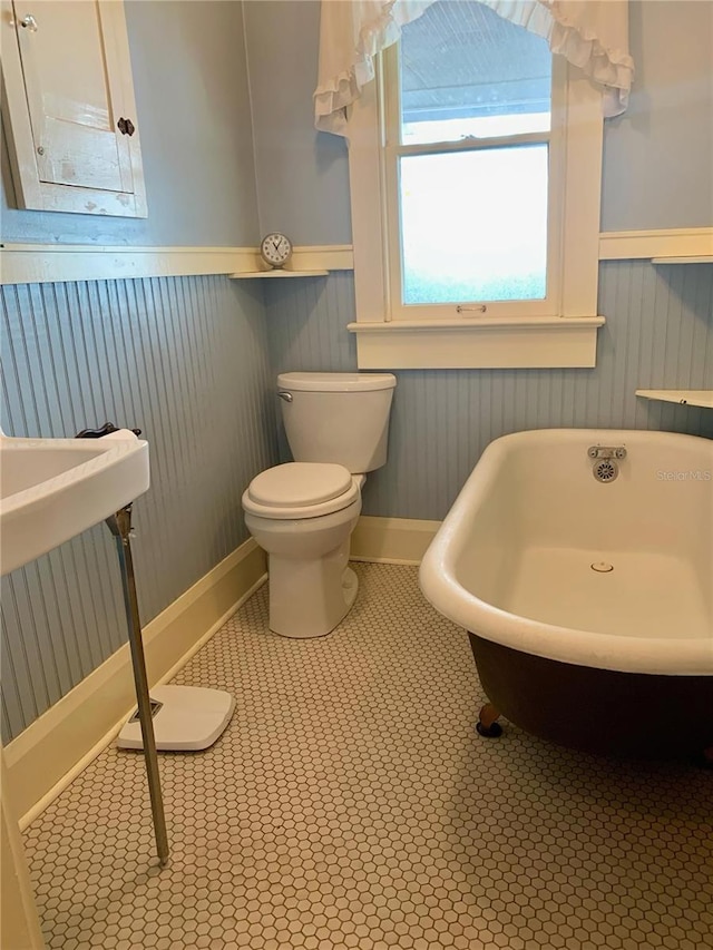 bathroom with a bath, tile patterned floors, and toilet