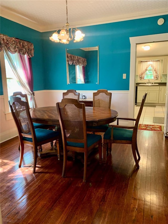 dining area featuring wood-type flooring, sink, and an inviting chandelier