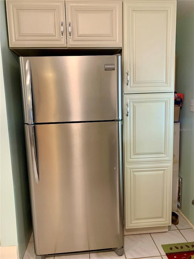 kitchen featuring cream cabinets, light tile patterned floors, and stainless steel refrigerator