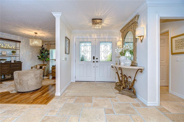 entrance foyer with a notable chandelier, crown molding, and french doors