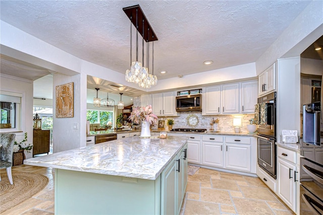 kitchen featuring white cabinetry, appliances with stainless steel finishes, light stone countertops, and a kitchen island