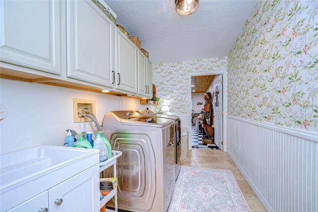 washroom featuring independent washer and dryer, cabinets, and a textured ceiling