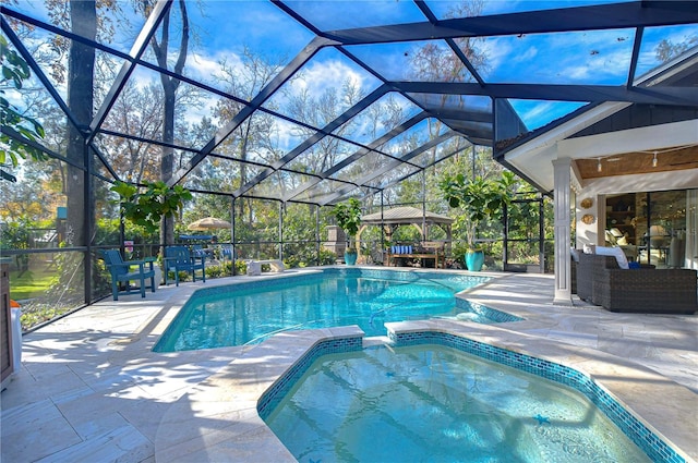 view of swimming pool featuring an in ground hot tub, outdoor lounge area, a patio area, and glass enclosure