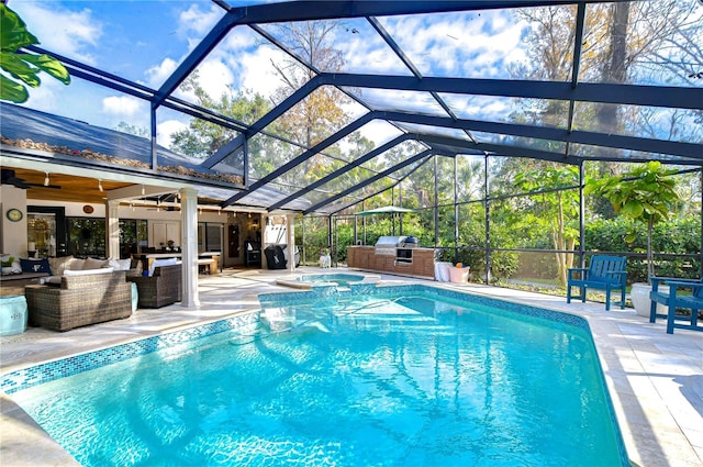 view of pool with an outdoor kitchen, glass enclosure, ceiling fan, an outdoor living space, and a patio