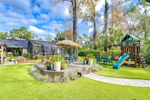 view of yard with a playground, a wooden deck, and glass enclosure