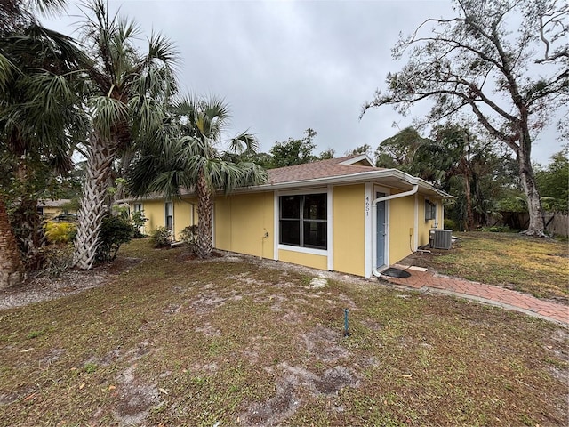 view of property exterior featuring central AC unit and a lawn