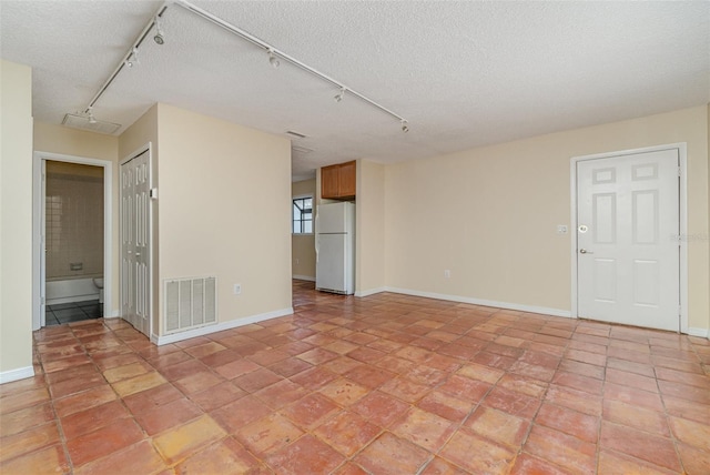 unfurnished room with light tile patterned floors, rail lighting, and a textured ceiling