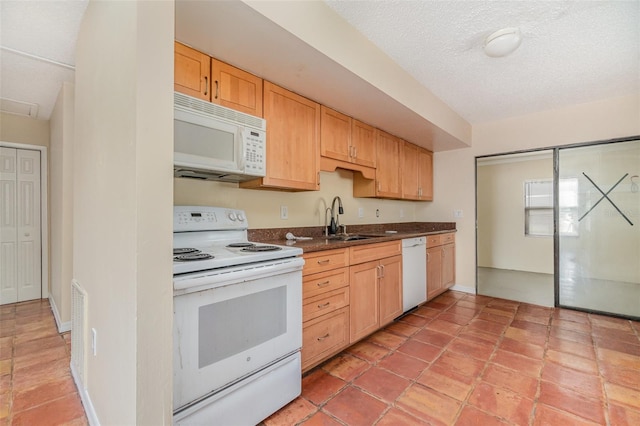 kitchen featuring white appliances, sink, a textured ceiling, and light brown cabinets