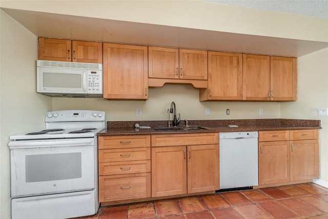 kitchen with white appliances, sink, and dark stone countertops