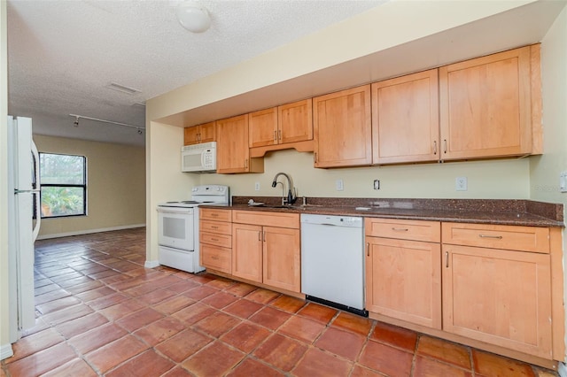 kitchen with sink, white appliances, a textured ceiling, and light brown cabinets