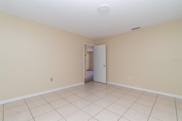 tiled empty room with a textured ceiling