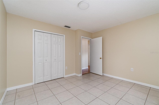 unfurnished bedroom with a textured ceiling, a closet, and light tile patterned floors