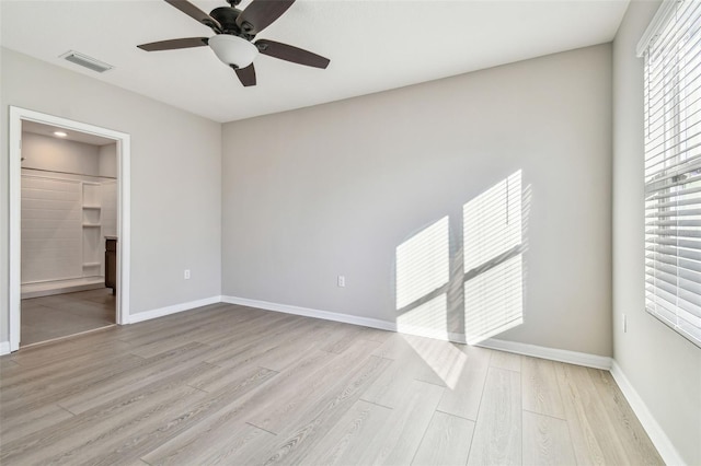 unfurnished bedroom featuring a walk in closet, light hardwood / wood-style floors, a closet, and ceiling fan