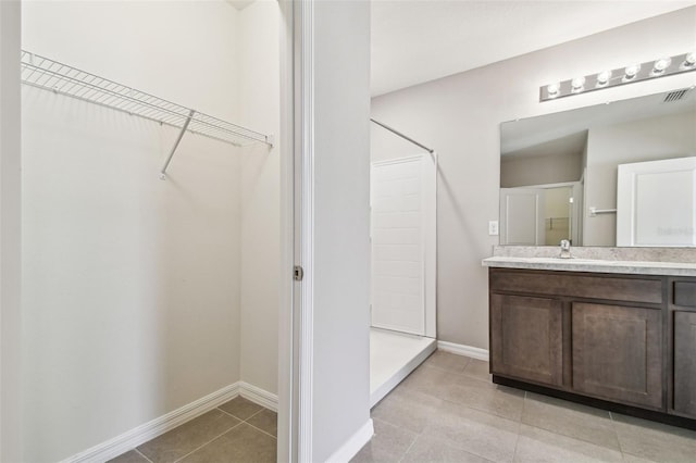 bathroom featuring tile patterned flooring, vanity, and a shower