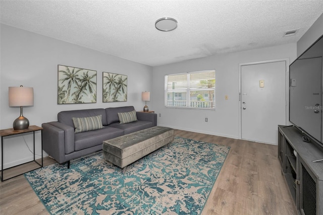 living room with a textured ceiling, visible vents, and wood finished floors