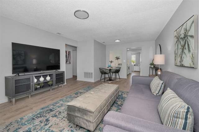 living area with a textured ceiling, wood finished floors, and visible vents