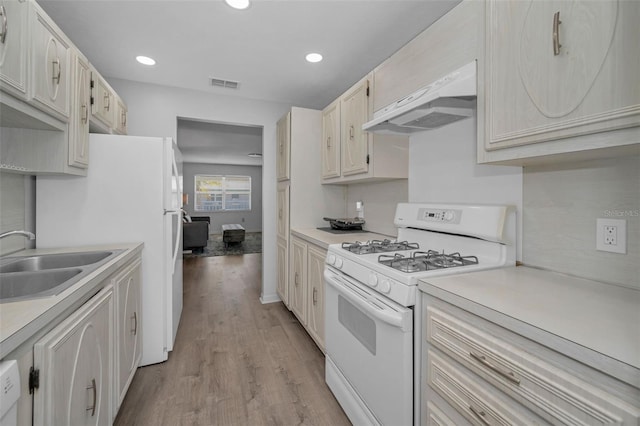 kitchen with under cabinet range hood, a sink, visible vents, white range with gas cooktop, and light countertops