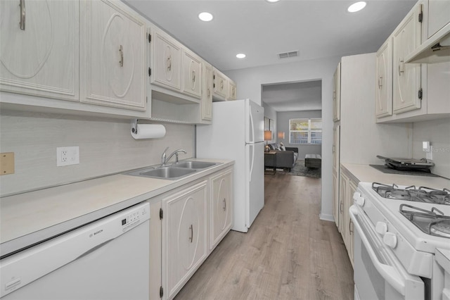 kitchen featuring light countertops, visible vents, a sink, white appliances, and under cabinet range hood