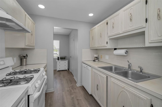 kitchen with white appliances, light countertops, a sink, and under cabinet range hood