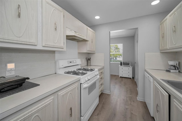 kitchen featuring recessed lighting, white appliances, wood finished floors, baseboards, and light countertops