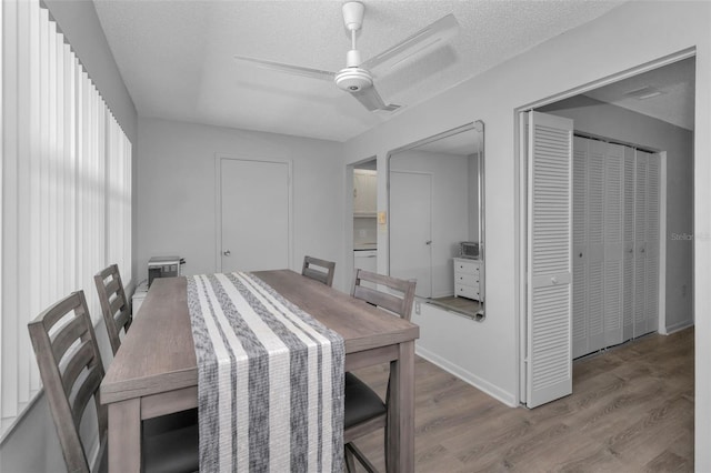 dining room featuring ceiling fan, a textured ceiling, baseboards, and wood finished floors