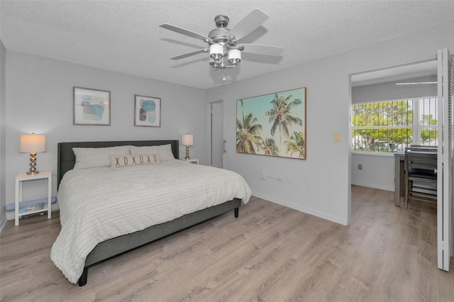 bedroom featuring a textured ceiling, ceiling fan, light wood-type flooring, and baseboards