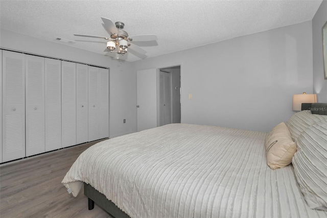 bedroom with a textured ceiling, a closet, and wood finished floors