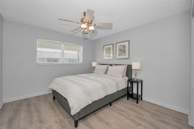 bedroom featuring a textured ceiling, baseboards, and wood finished floors