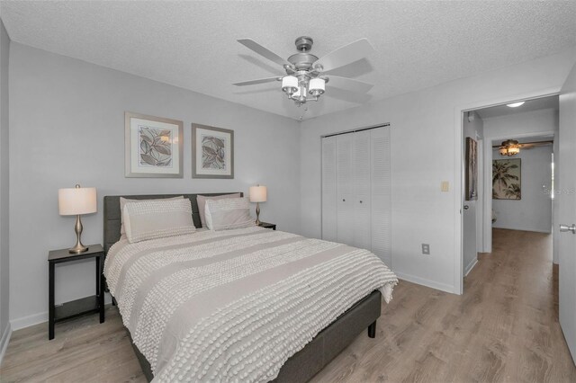 bedroom with light wood-style flooring, a textured ceiling, baseboards, and a closet