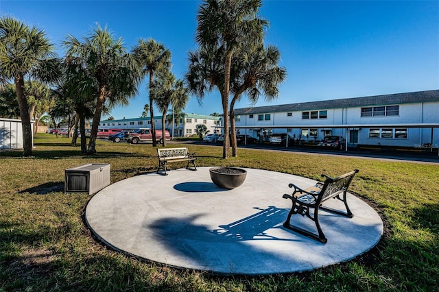 view of property's community with a patio area, a lawn, and a fire pit