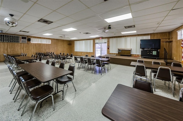 dining area with visible vents, wood walls, and speckled floor