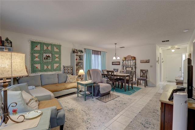 living room with ceiling fan, light tile patterned floors, and a textured ceiling