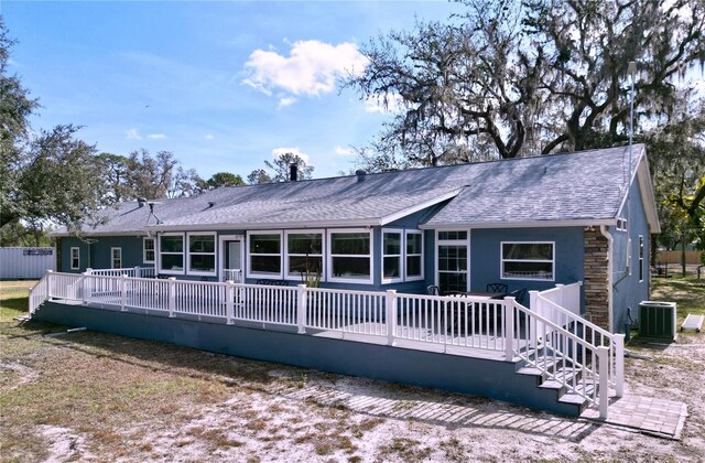 rear view of house with roof with shingles, central AC unit, and a wooden deck