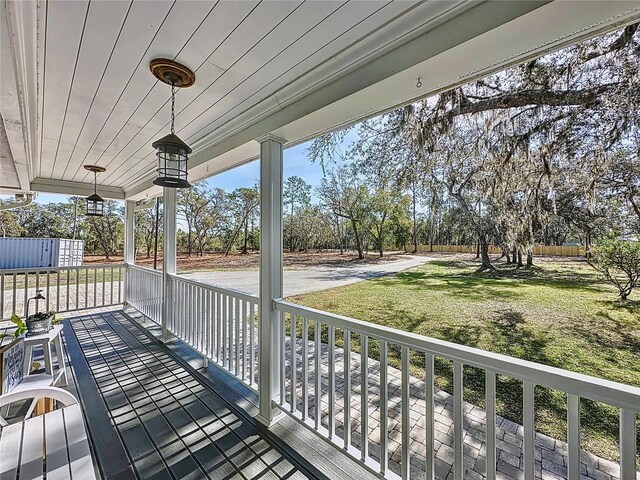 wooden terrace with a lawn and a porch