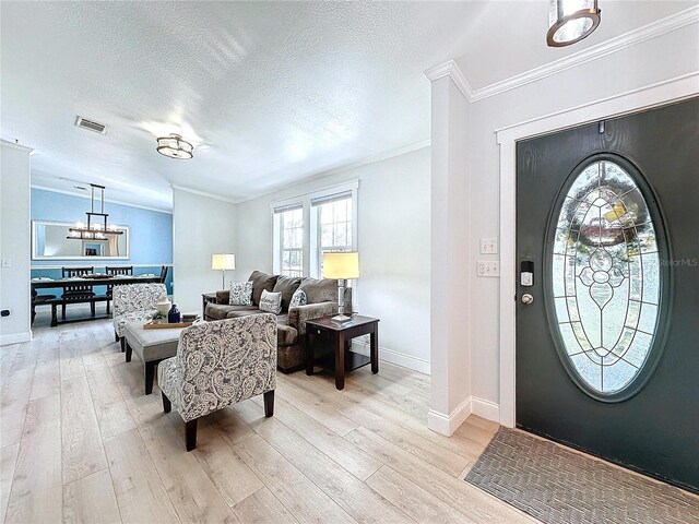 foyer entrance with ornamental molding, a textured ceiling, and light wood-type flooring