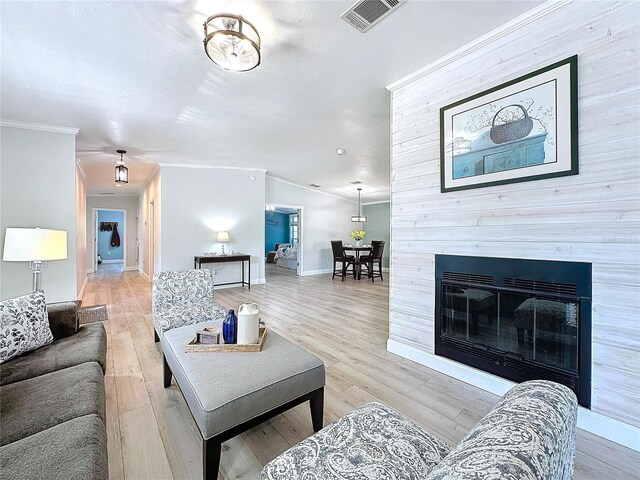 living room with ornamental molding, vaulted ceiling, light hardwood / wood-style floors, and a textured ceiling