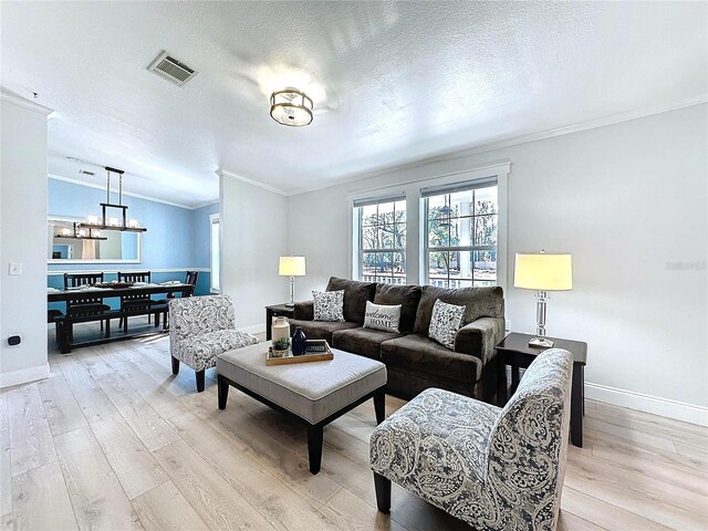 living room with crown molding, a textured ceiling, and light wood-type flooring