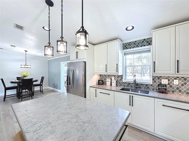 kitchen featuring pendant lighting, white cabinets, a sink, and stainless steel fridge with ice dispenser