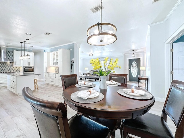 dining area featuring light wood finished floors, visible vents, ornamental molding, and baseboards