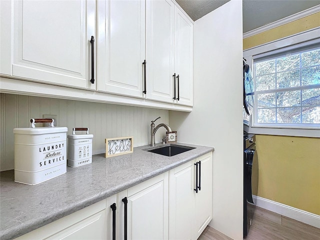 interior space with sink, wood-type flooring, and white cabinets